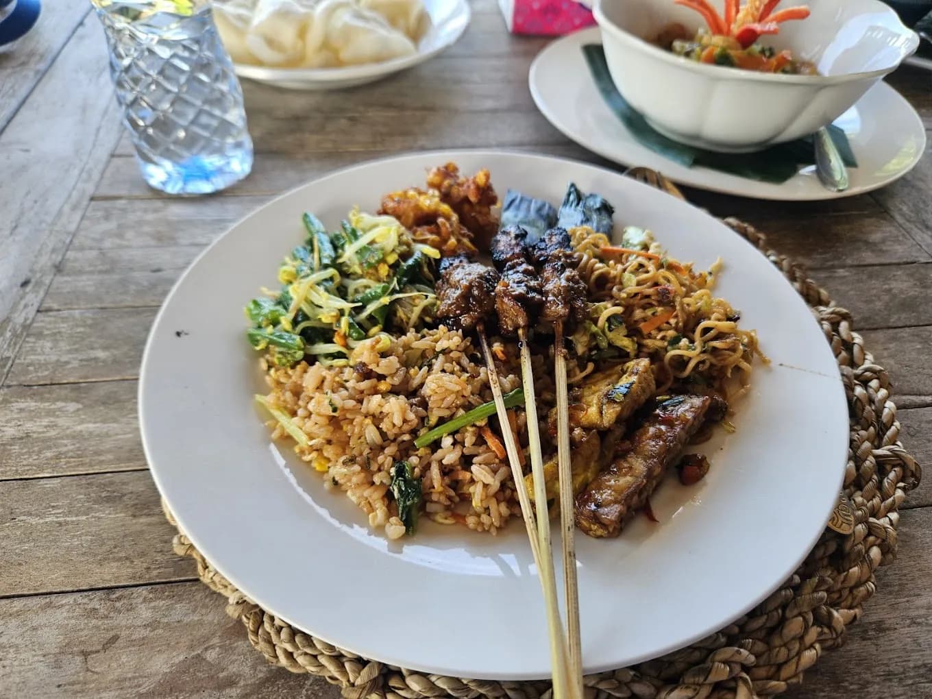 A class plate of nasi goreng, sate lilit on lemongrass, corn fritters, and sambal at Warung Tumang Bali, on a food day near Ubud