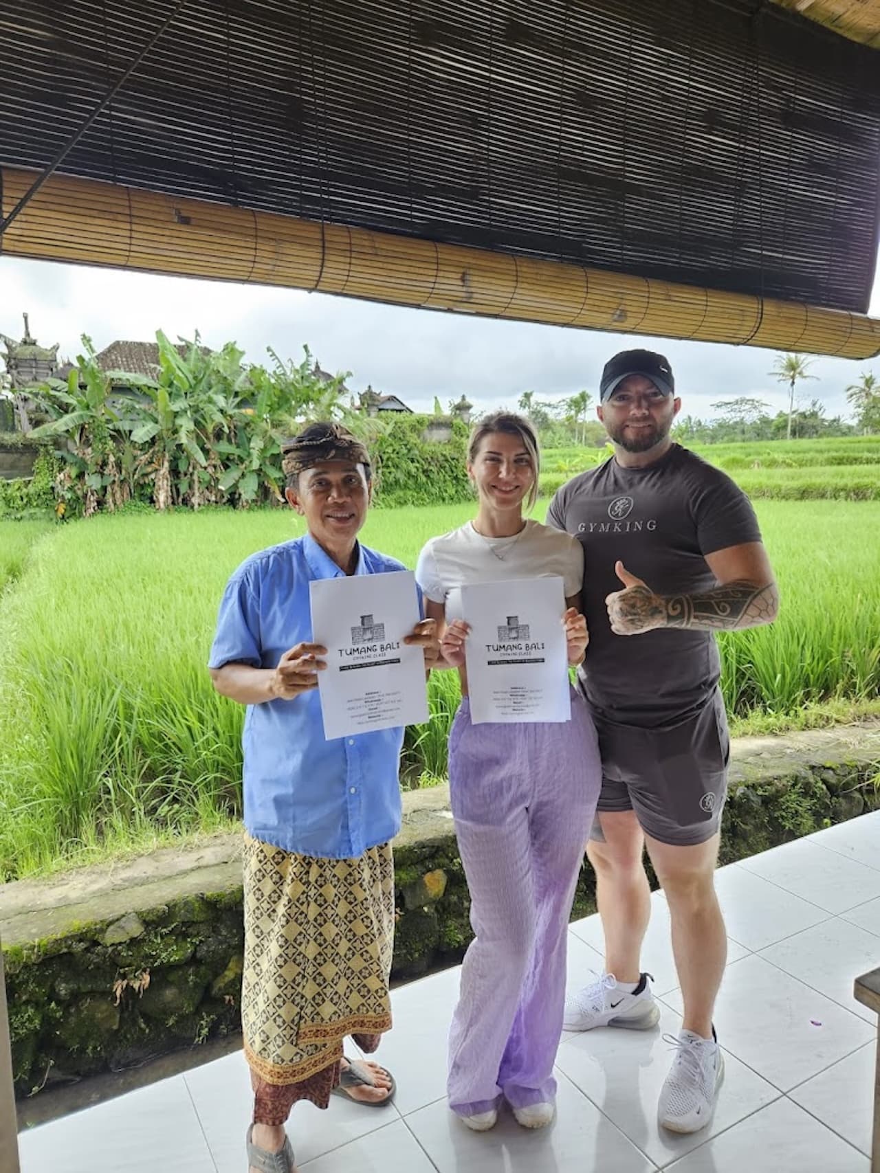 Cooking certificates held up in front of a green rice field
