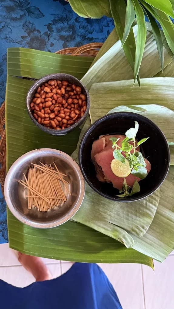 Satay sticks, roasted peanuts, and grilled meat on a banana leaf in Petulu, on a food day near Ubud