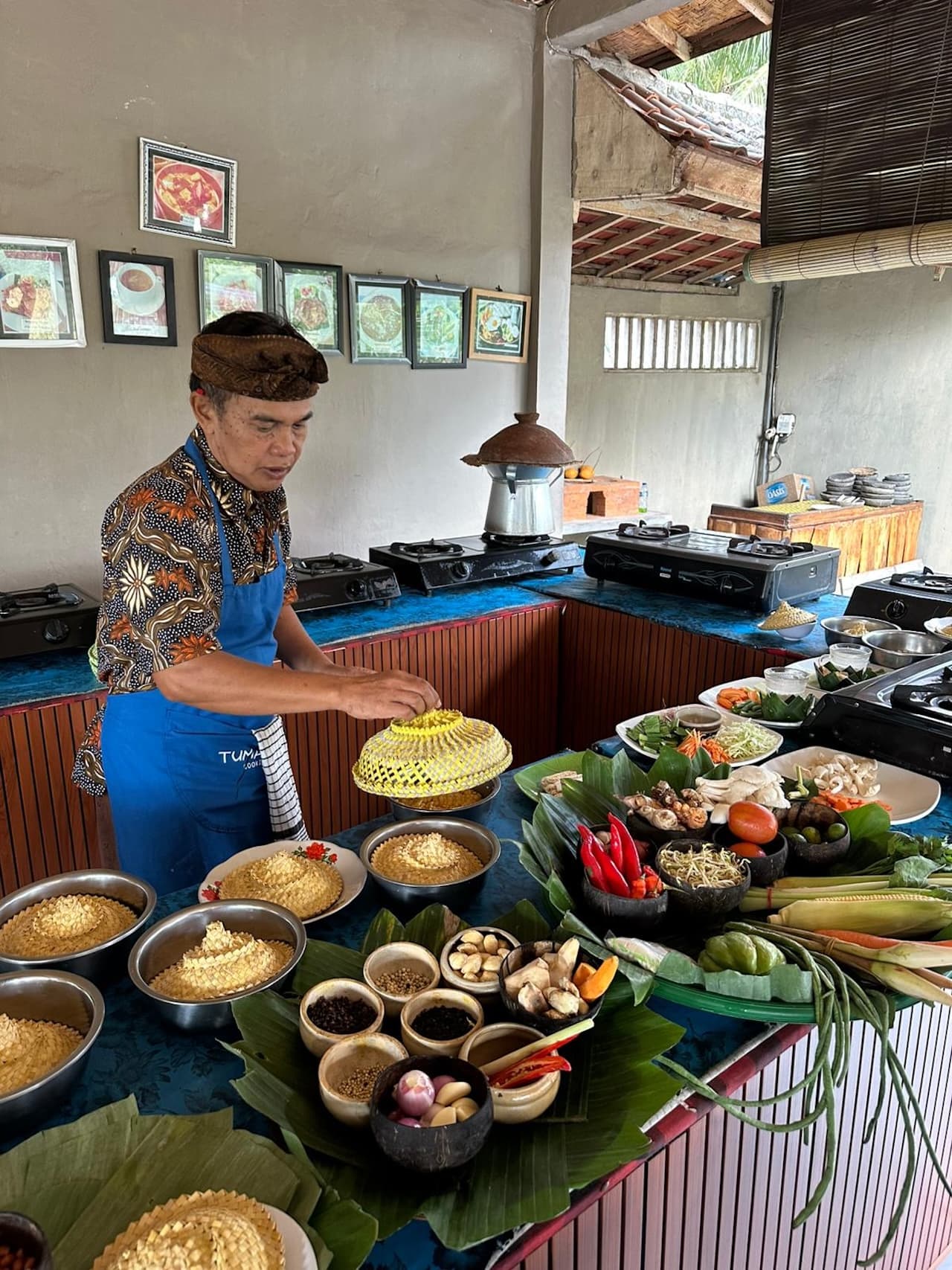 A wooden table set with bowls of ground spices, chilies, grated coconut, and banana leaves, on a food day near Ubud